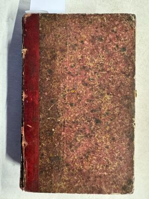 un vieux livre posé sur une table blanche, à côté d'une feuille de papier