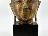 tête en bronze d'une statue de Bouddha posée sur un socle en marbre noir