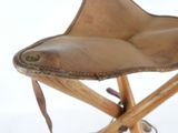 a brown leather chair that is on a wooden stand