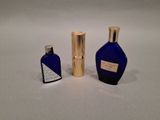 two bottles of perfume sitting next to each other on a white surface