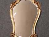 un miroir accroché au mur, avec un cadre doré