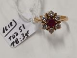 un gros plan d'une bague en or sertie d'une pierre rouge entourée de diamants
