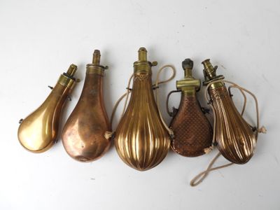 four brass vases with handles are lined up on a white surface