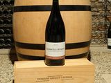 une bouteille de vin posée sur un tonneau en bois