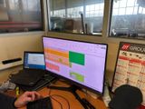 un homme assis à un bureau, devant un ordinateur portable et un écran