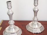 two silver candlesticks sitting on a wooden table