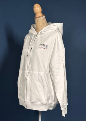 a white hoodie on a mannequin stand against a blue wall