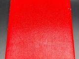 an old red book sitting on top of a black table