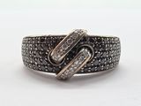 un gros plan d'une bague sertie d'un diamant noir et blanc sur une surface blanche