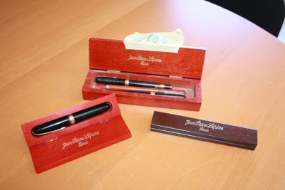 two pens and a pen case on a wooden table