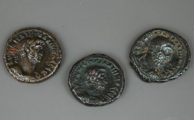 trois pièces de monnaie romaines anciennes posées les unes à côté des autres sur une table