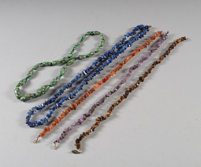 un ensemble de cinq colliers en perles posés sur un fond blanc
