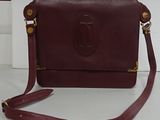 burgundy leather handbag with gold accents and a strap