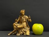 a statue of a man sitting on a chair next to an apple