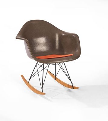un fauteuil à bascule avec une assise marron et un coussin orange