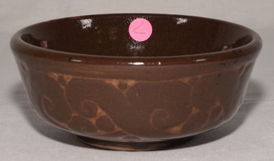 un bol marron avec un point rose dessus