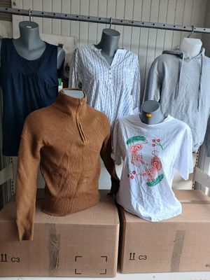 Plusieurs mannequins sont assis sur des cartons dans un magasin de vêtements.