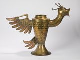 une image représentant un vase en laiton sur lequel est représenté un oiseau