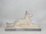 statue of a dog laying down on a white surface