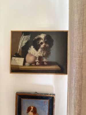a painting of a dog sitting on a shelf next to a painting of a dog