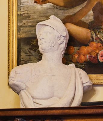 une statue représentant une femme tenant un fruit devant un tableau
