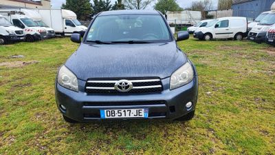 Une Toyota RAV noire est garée dans un champ herbeux.