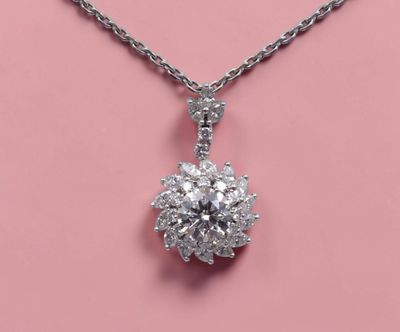 un pendentif en forme de fleur en diamant, suspendu à une chaîne, sur fond rose