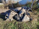 un tas d'ordures posé dans l'herbe, près d'une clôture
