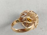 an image of a gold ring with a yellow stone in the center