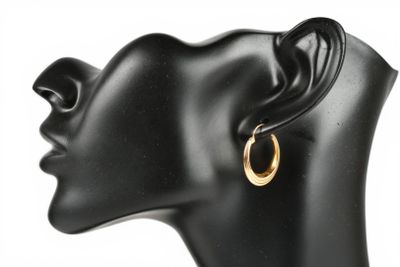 un gros plan sur la tête d'un mannequin portant une paire de boucles d'oreilles créoles en or