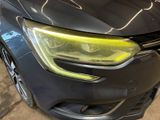 the front end of a black car with a yellow light on it
