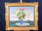 un tableau représentant des fleurs dans un vase bleu posé sur un chevalet