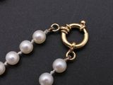necklace with pearls and a gold clasp on a black surface