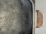 a metal pan with a handle that has a crack in it