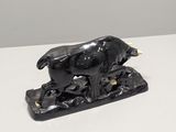 a black statue of a cow on a white surface