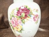 un vase blanc orné de fleurs roses et jaunes peintes dessus