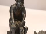 a statue of a man sitting on a stool next to a dog
