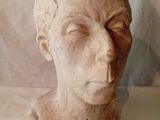 une sculpture en argile représentant une tête d'homme posée sur un tissu blanc
