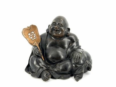 statue of a laughing laughing buddha holding a paddle and a ball