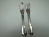 two forks that are sitting next to each other on a table