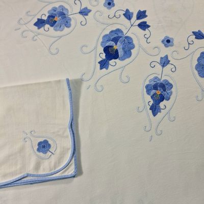 embroidered table cloth with blue flowers and vines on it