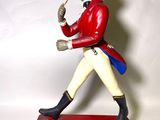 figurine représentant un homme vêtu d'un manteau rouge et d'un chapeau, tenant une pipe