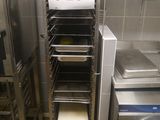 several trays of food are stacked on a rack in a kitchen