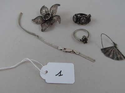 a lot of silver jewelry on a table with a price tag
