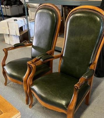 deux fauteuils en cuir vert dans une pièce équipée d'une table et de chaises
