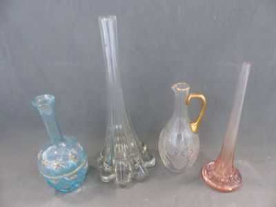 Plusieurs vases en verre de différentes couleurs sont alignés sur une surface grise