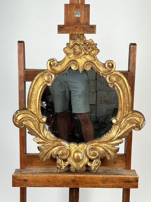 un miroir posé sur un pied, devant lequel se tient un homme