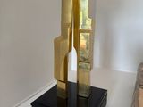 a gold sculpture on a black base on a white table