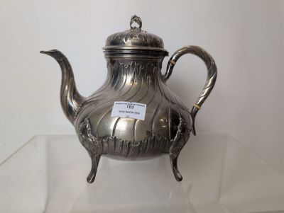 a silver tea pot sitting on a glass table