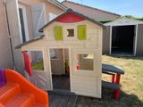 a small wooden house with a slide in the yard